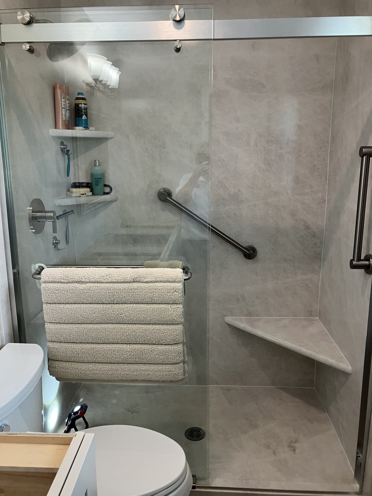 Finished walk-in shower with a grab bar and corner seat